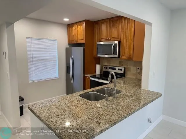 a kitchen with kitchen island a sink stainless steel appliances and a counter top space