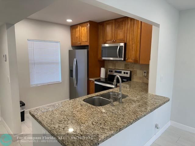 7605 Northwest 5th Court, Unit 208 Margate, FL 33063 - Photo 5 of 25 a kitchen with kitchen island a sink stainless steel appliances and a counter top space