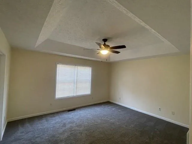 an empty room with windows and fan