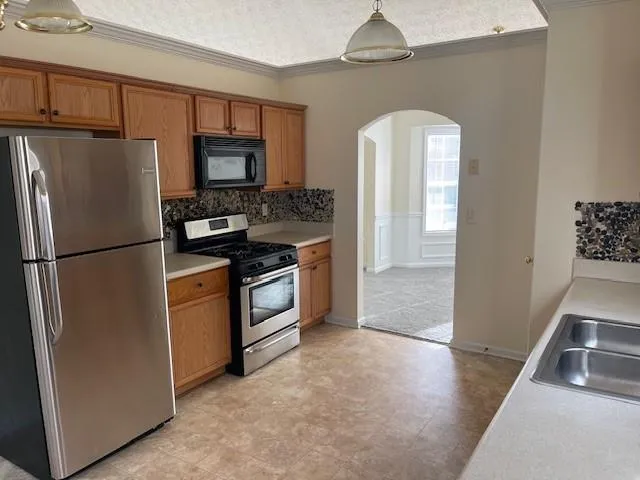 a kitchen with stainless steel appliances granite countertop a refrigerator a stove a sink and a refrigerator