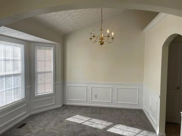 an empty room with chandelier fan and windows