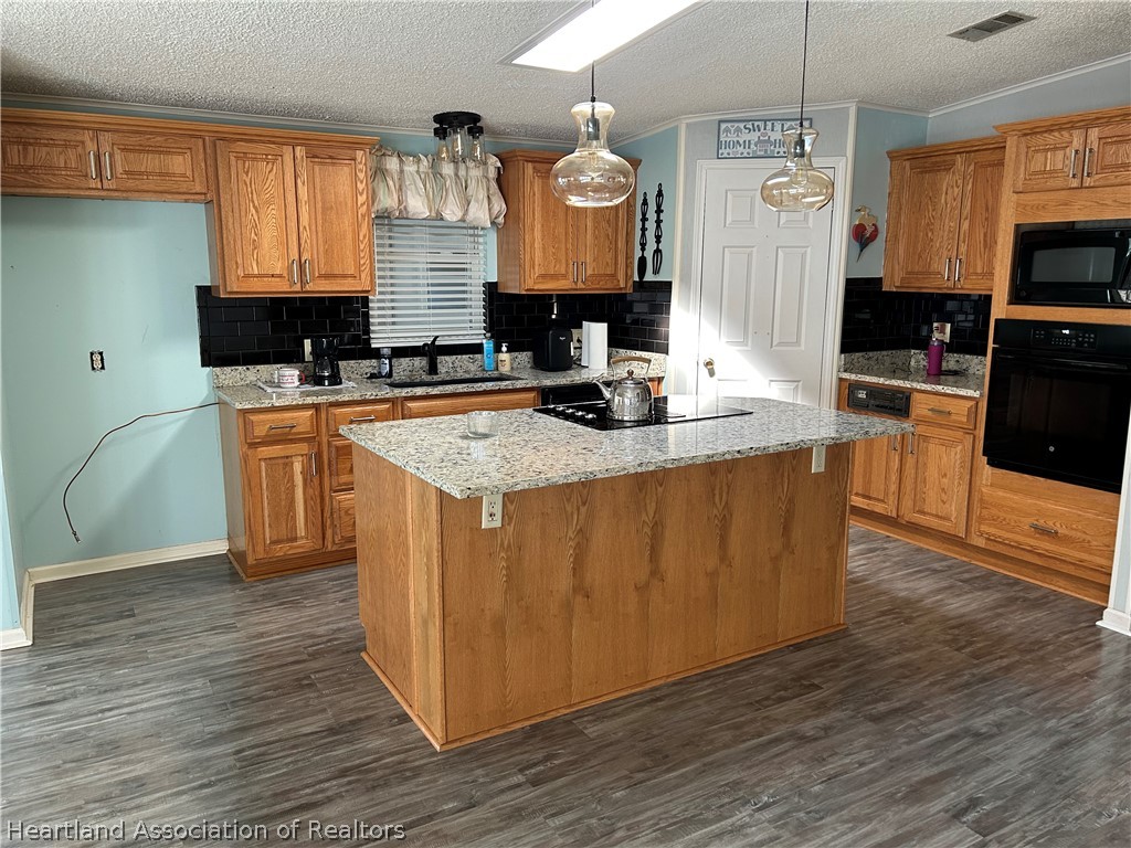337 Hickory Ridge Drive Sebring, FL 33876 - Photo 24 of 48 a kitchen with kitchen island granite countertop a stove top oven a sink a counter space and wooden floor