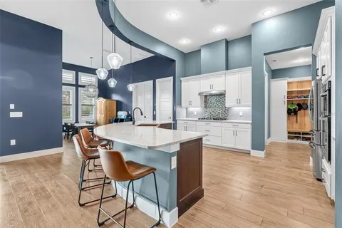 a kitchen with stainless steel appliances granite countertop a refrigerator a oven a sink a dining table and chairs with wooden floor