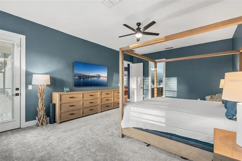 a bedroom with a large bed and a chandelier fan