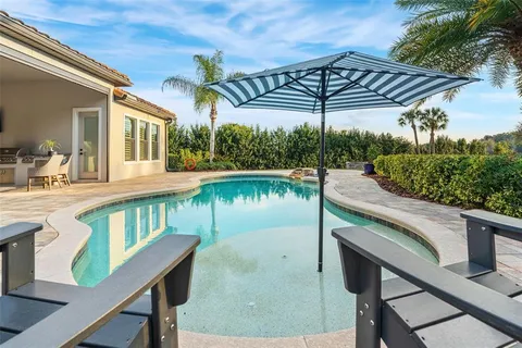 a view of a white house with a small yard and large trees