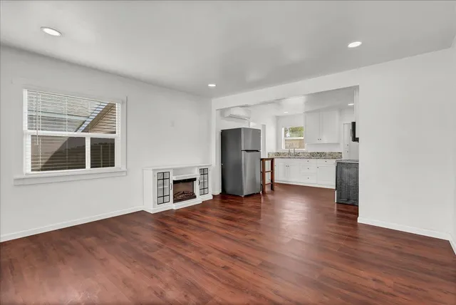 a view of an empty room with window and wooden floor