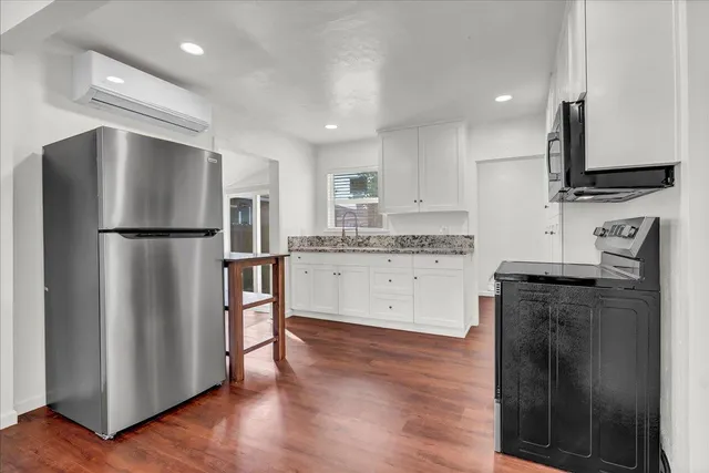 a kitchen with granite countertop white cabinets and stainless steel appliances