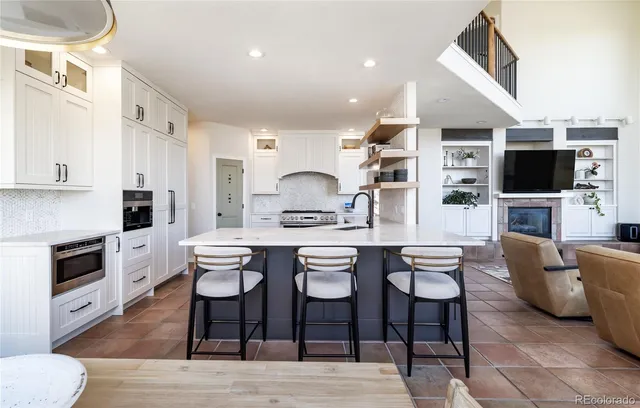 a dining hall with stainless steel appliances kitchen island granite countertop a dining table chairs and a refrigerator