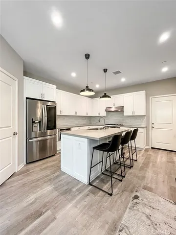 a kitchen with kitchen island a counter space a sink appliances and cabinets