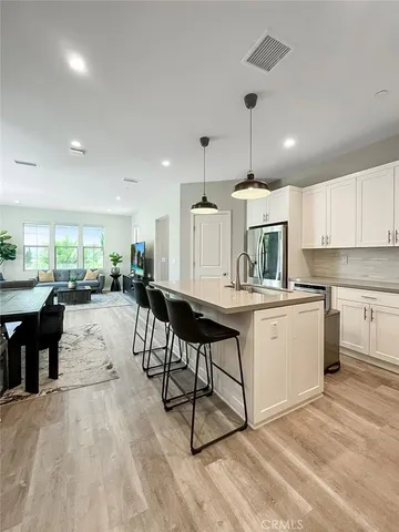 a kitchen with stainless steel appliances kitchen island granite countertop a stove a sink a refrigerator and white cabinets with wooden floor