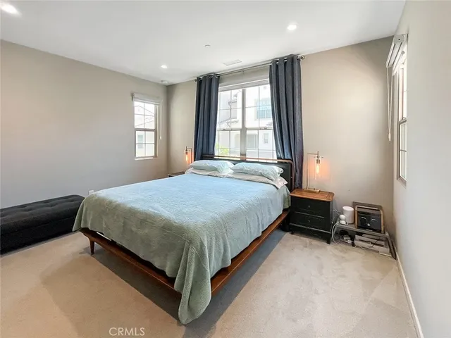 a bed sitting in a spacious bedroom next to a window and a dresser