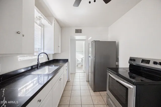 a kitchen with granite countertop a refrigerator and a stove top oven