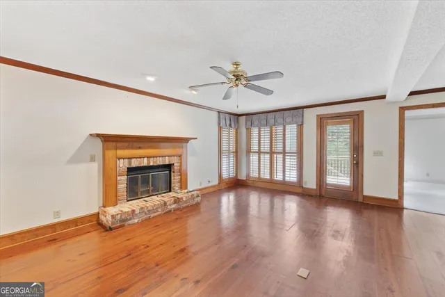 a view of an empty room with window and wooden floor