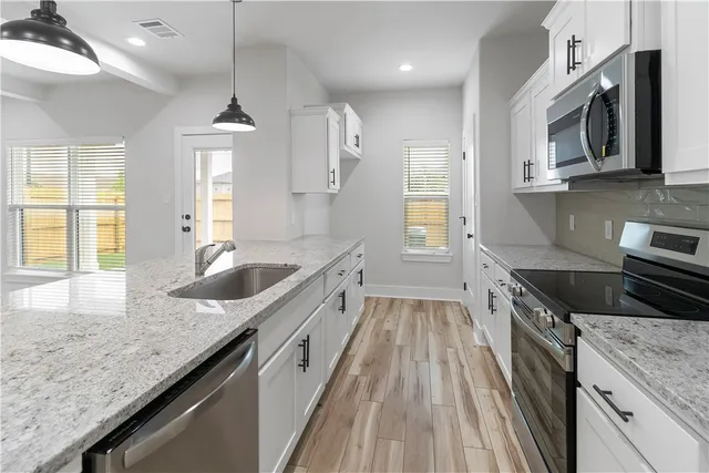 a kitchen with granite countertop stainless steel appliances sink stove microwave and cabinets