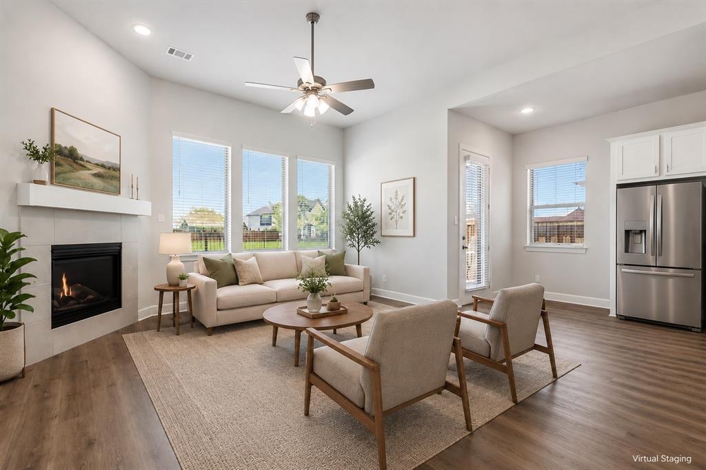 2813 Trinity Ridge Street Mansfield, TX 76063 - Photo 5 of 27 Open-concept living area featuring wood-finish flooring, a contemporary fireplace with a floating mantel, and abundant natural light from multiple windows
