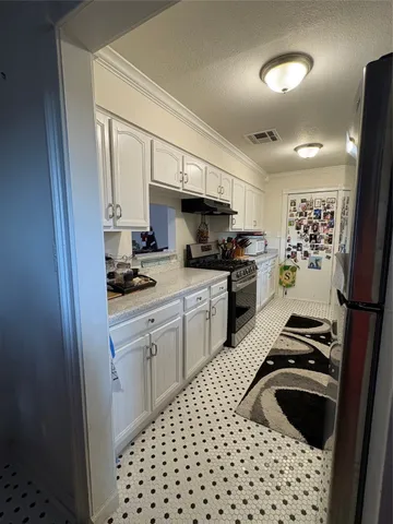 a kitchen with a refrigerator a sink and white cabinets
