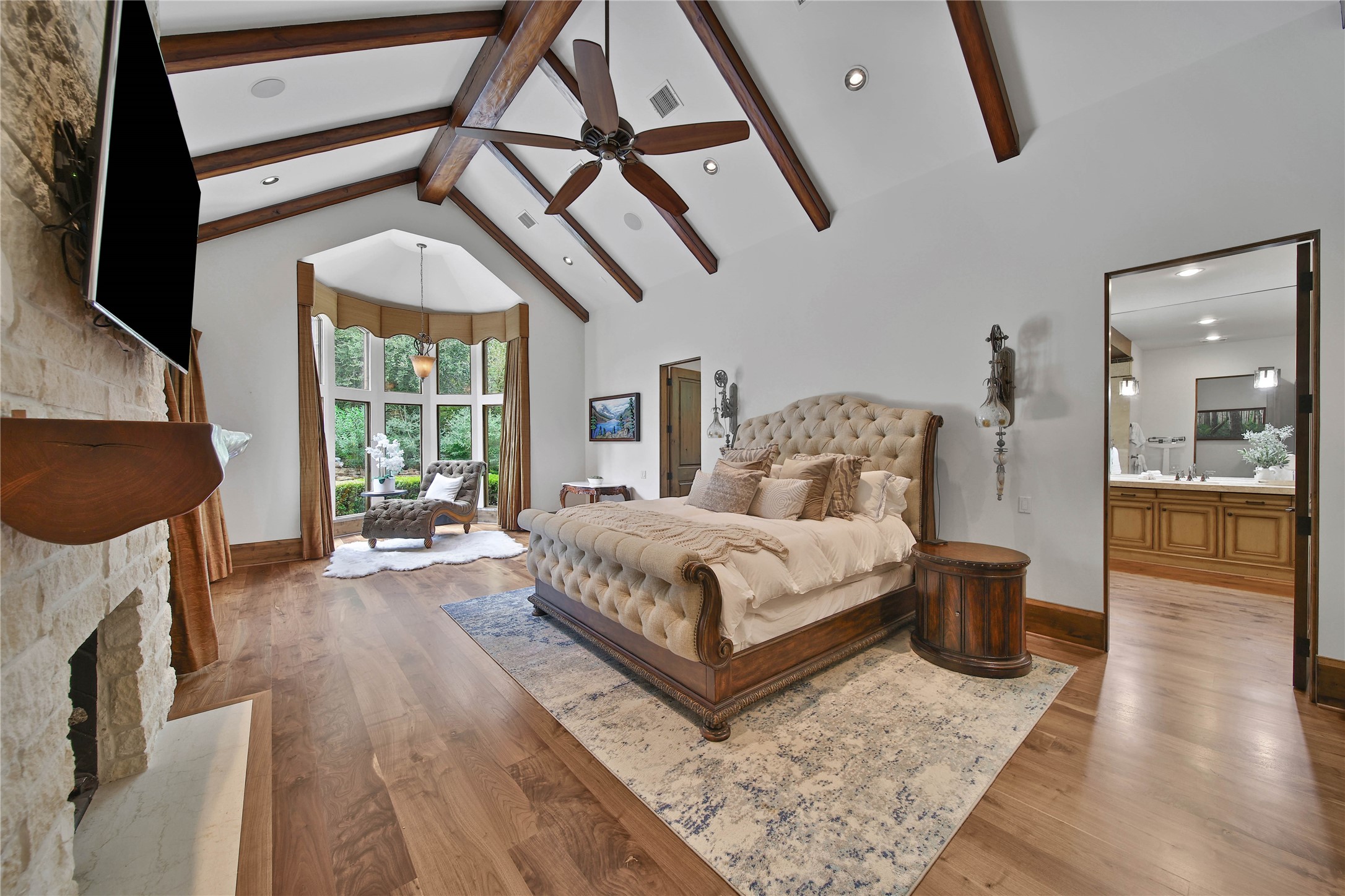 The primary bedroom suite is spacious, with  vaulted beamed ceilings, a fireplace, and beautiful natural light.