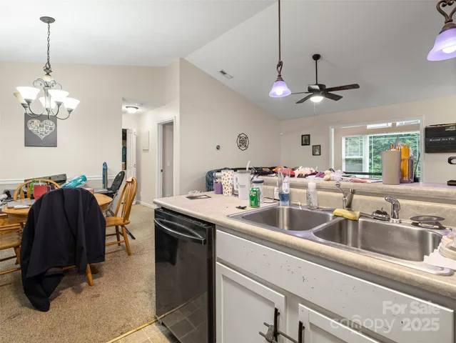 a kitchen with a sink chandelier and living room view