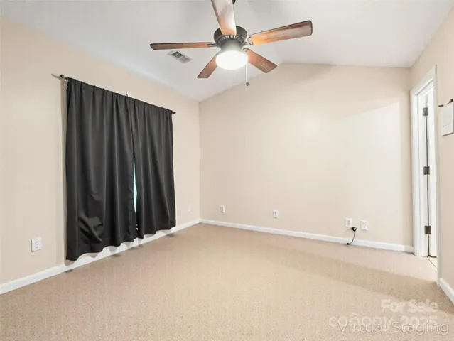 an empty room with ceiling fan and window