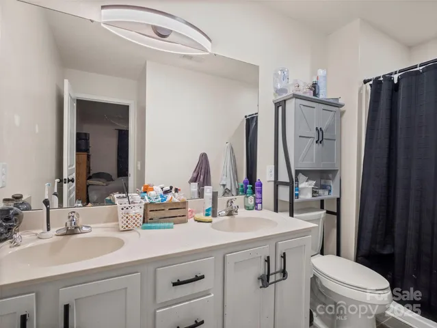 a bathroom with double vanity sink a mirror a toilet and a window
