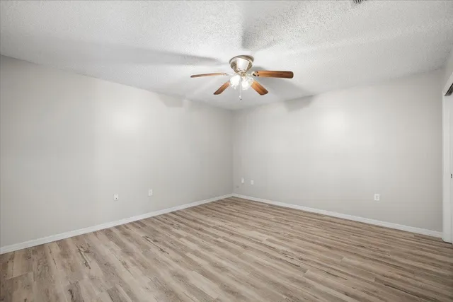 a view of a room with wooden floor and ceiling fan