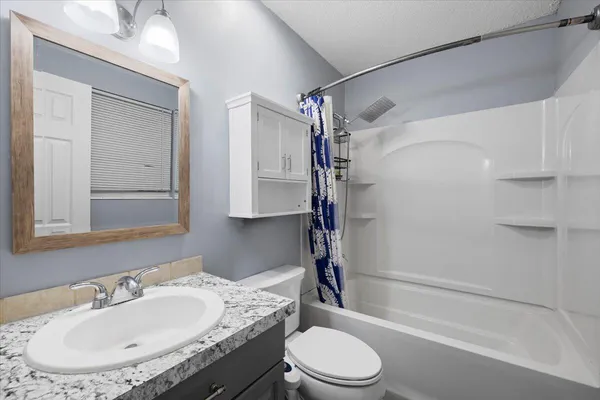 a bathroom with a granite countertop sink toilet and shower