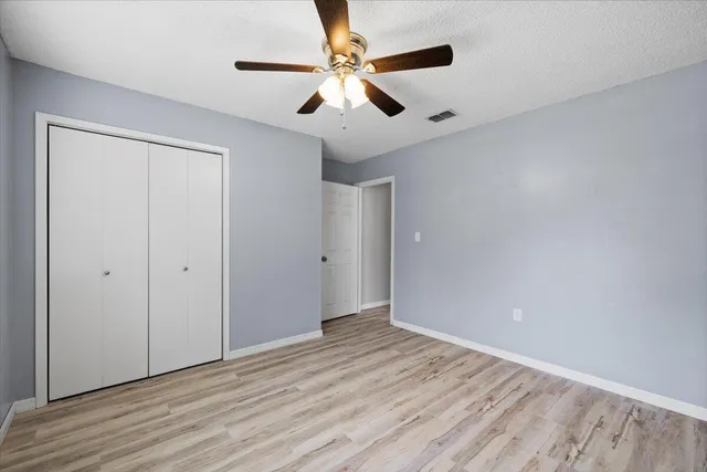an empty room with wooden floor chandelier fan and closet area