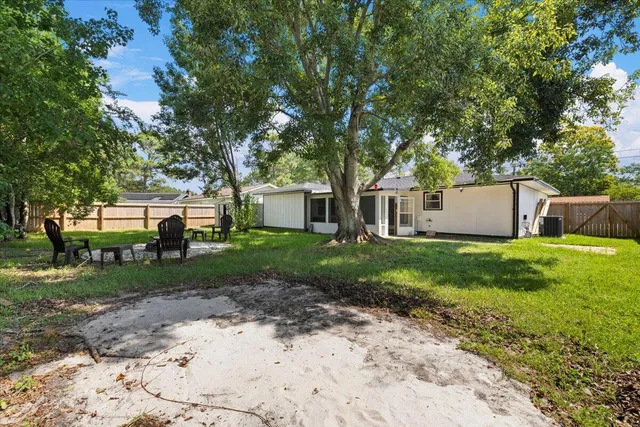 a view of a house with a yard and a large tree