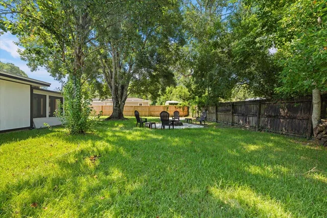a backyard of a house with table and chairs plants and large tree