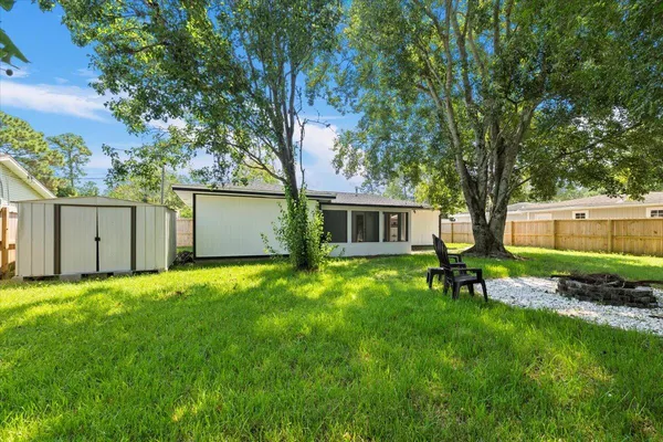 a view of a backyard with table and chairs and a large tree