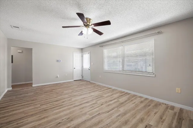 a view of an empty room with window and wooden floor