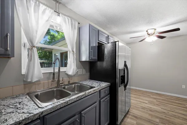 a kitchen with stainless steel appliances granite countertop a sink a refrigerator and a window