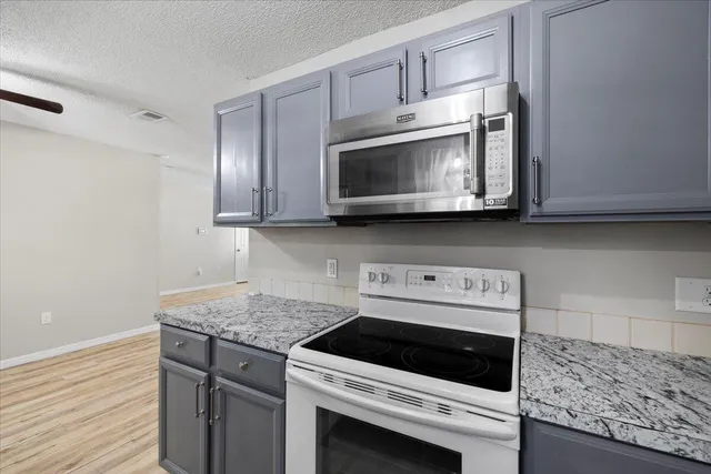a kitchen with stainless steel appliances granite countertop a stove microwave and cabinets
