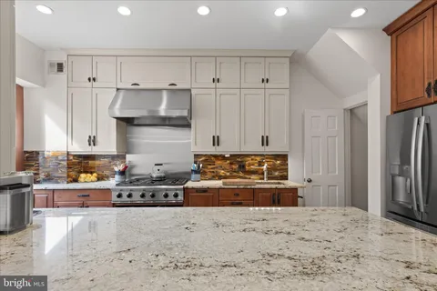 a large kitchen with stainless steel appliances kitchen island granite countertop a large counter top a sink and a refrigerator