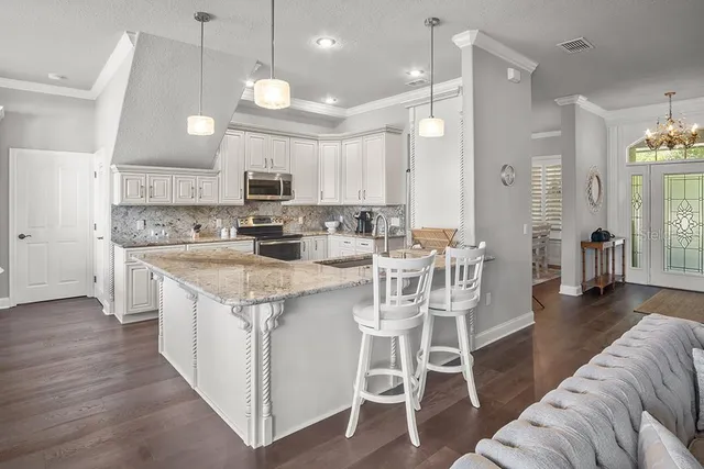 a large kitchen with stainless steel appliances kitchen island granite countertop a stove a sink a refrigerator and a dining table with wooden floor
