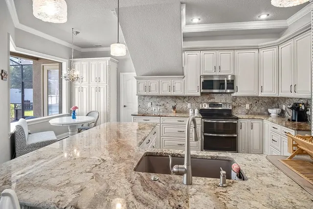 a kitchen with stainless steel appliances kitchen island granite countertop a stove sink and cabinets