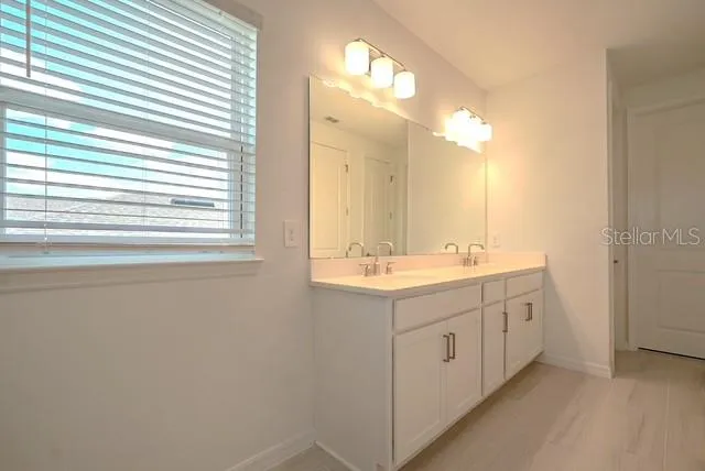 a bathroom with a double vanity sink and mirror with window