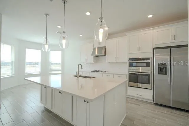 a kitchen with kitchen island a sink stainless steel appliances and cabinets