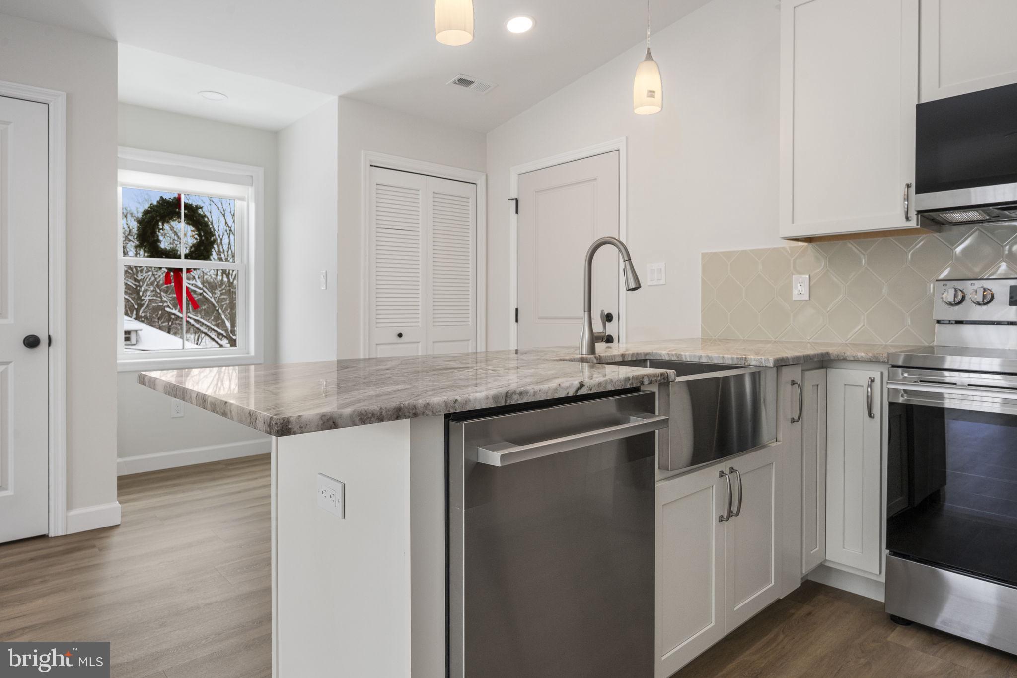 2185 Kimberton Road, Unit 5 Phoenixville, PA 19460 - Photo 20 of 36 a kitchen with granite countertop a sink and a stove top oven with wooden floor
