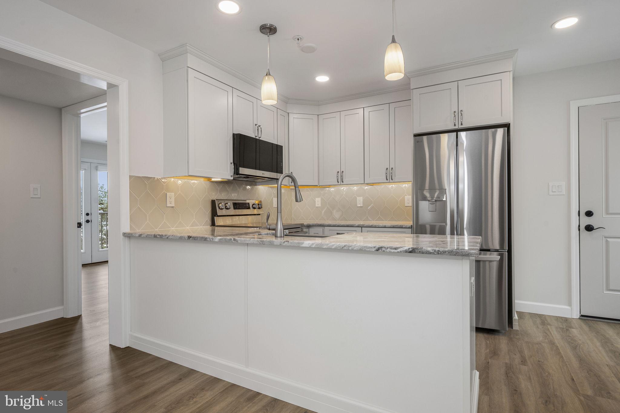 2185 Kimberton Road, Unit 5 Phoenixville, PA 19460 - Photo 10 of 36 a kitchen with stainless steel appliances granite countertop a refrigerator a sink a stove a microwave and wooden floor