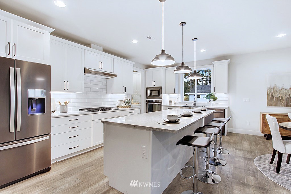 17718 Clover Road Bothell, WA 98012 - Photo 2 of 24 a kitchen with stainless steel appliances kitchen island granite countertop a sink a stove a refrigerator and chairs