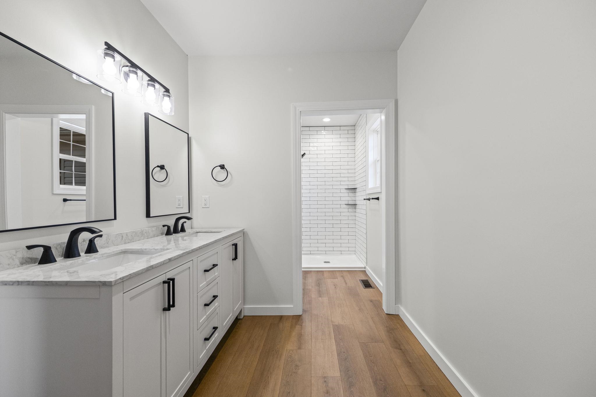 835 Curve Woodville Road Gates, TN 38037 - Photo 15 of 30 Bathroom with double vanity, a tile shower, and light wood-style floors