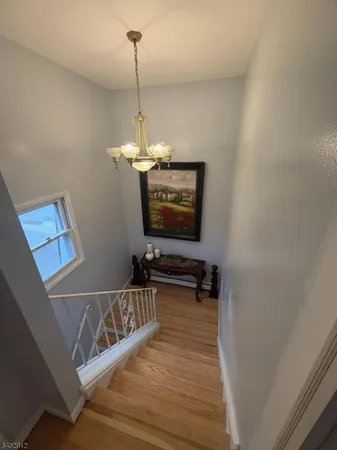 a view of a room with wooden floor staircase and a chandelier