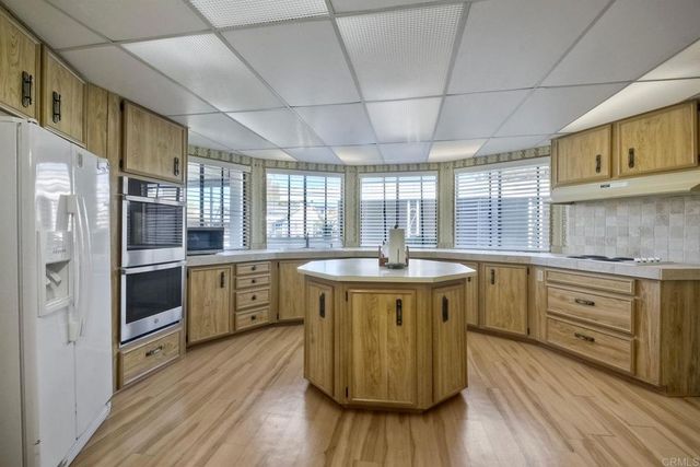 a kitchen with stainless steel appliances granite countertop a sink a stove and a wooden cabinets