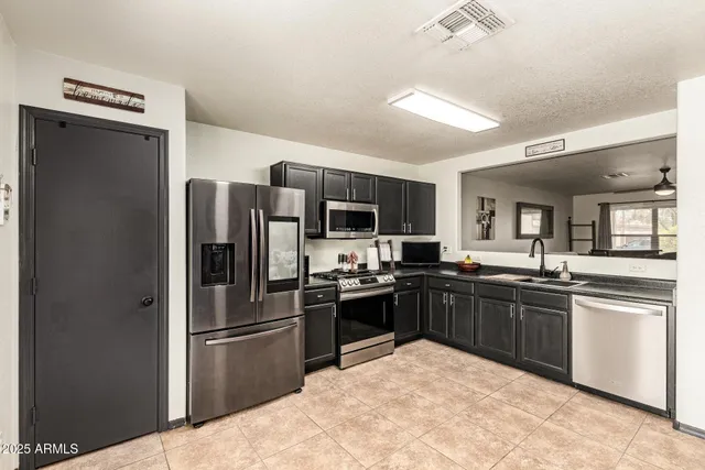 a kitchen with stainless steel appliances kitchen island granite countertop a refrigerator stove and sink