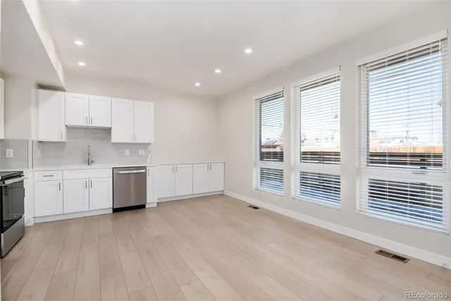 a kitchen with white cabinets and wooden floor