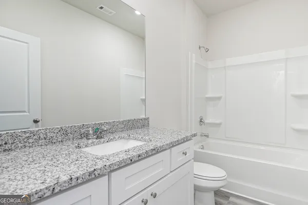 a bathroom with a granite countertop sink a toilet and bathtub