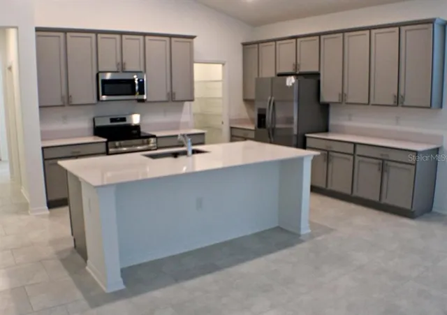 a kitchen with granite countertop a refrigerator stove top oven a sink and dishwasher