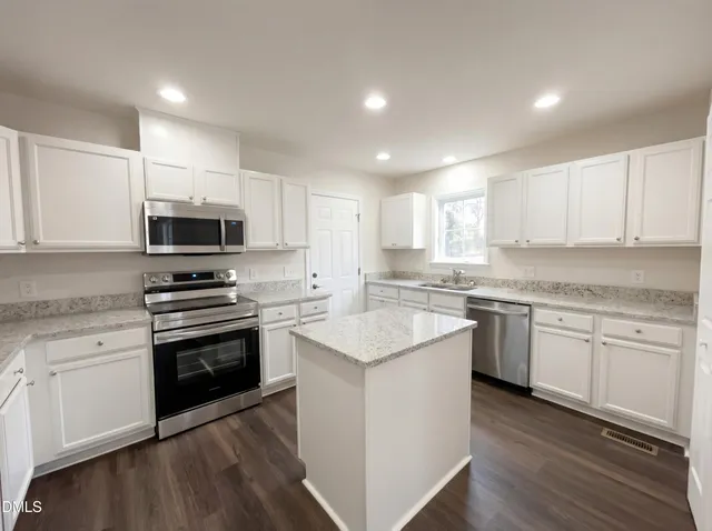 a kitchen with sink a microwave and cabinets