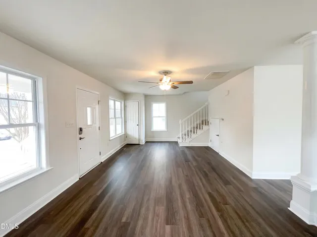 an empty room with wooden floor and windows